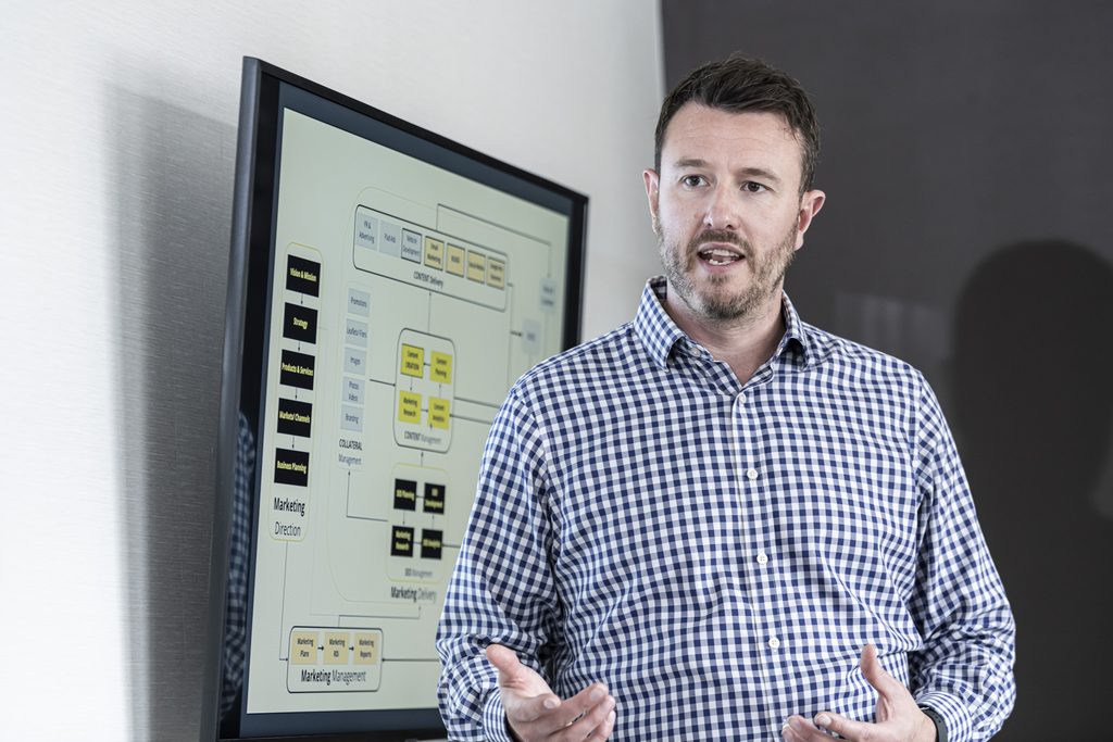 Fred Warner speaking in front of a presentation screen